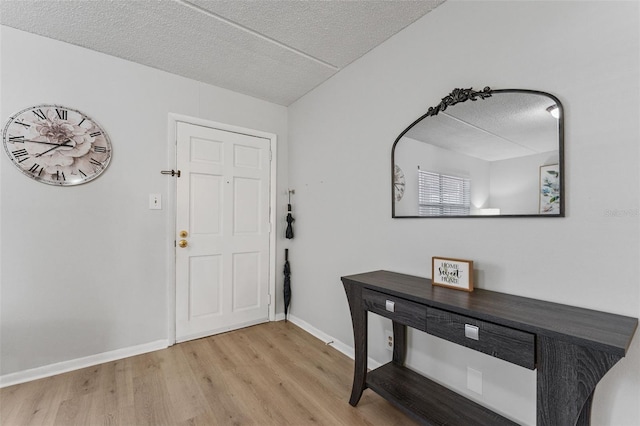 foyer featuring a textured ceiling, baseboards, and wood finished floors