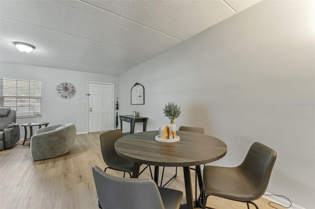 dining area featuring light wood-type flooring and a textured ceiling