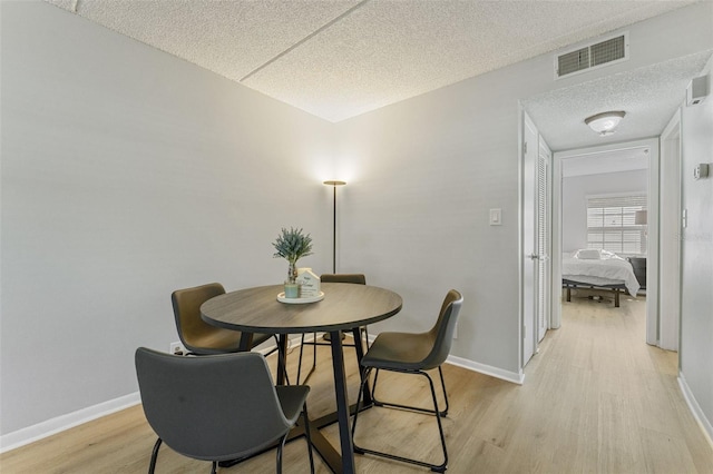 dining space featuring light wood-style flooring, baseboards, and visible vents