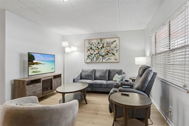 living area featuring a textured ceiling, baseboards, and wood finished floors