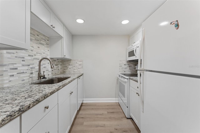 kitchen with light stone countertops, light wood-style floors, white appliances, white cabinetry, and a sink