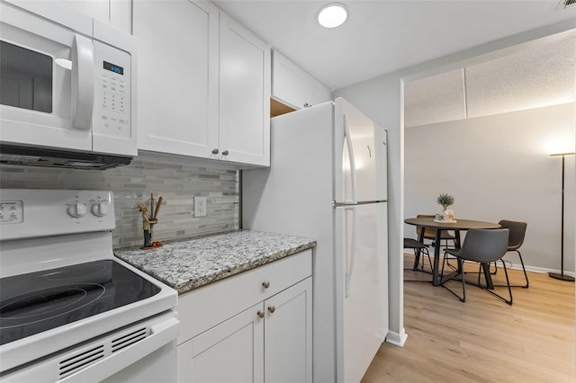 kitchen featuring white appliances, light stone counters, light wood-style floors, white cabinetry, and tasteful backsplash