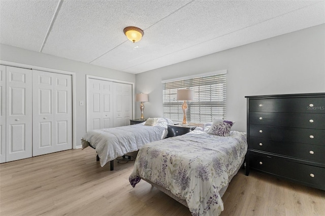 bedroom with wood finished floors, two closets, and a textured ceiling