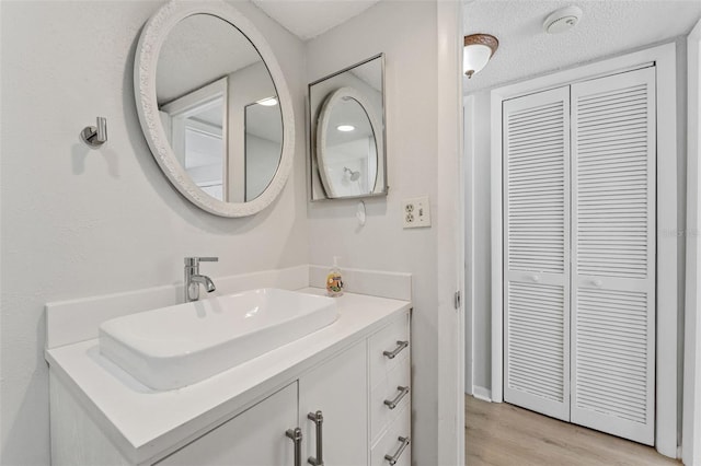 bathroom featuring vanity, wood finished floors, a closet, and a textured ceiling