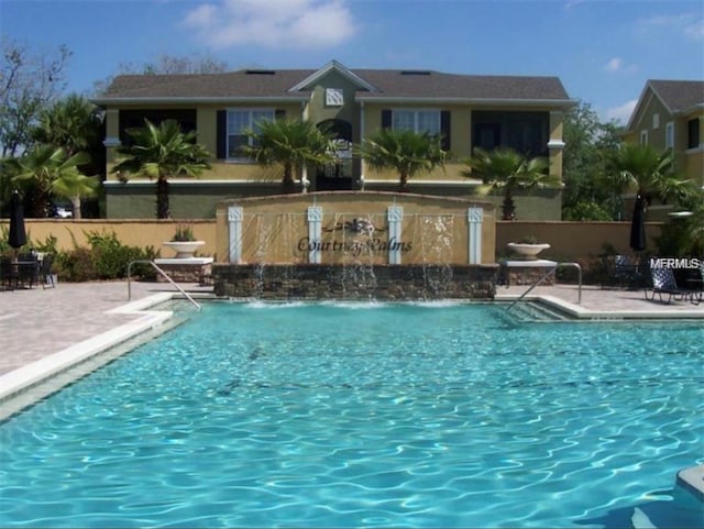 pool with a patio area and fence