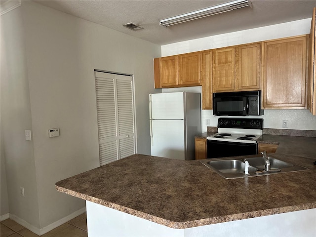 kitchen with electric stove, dark countertops, freestanding refrigerator, a sink, and black microwave