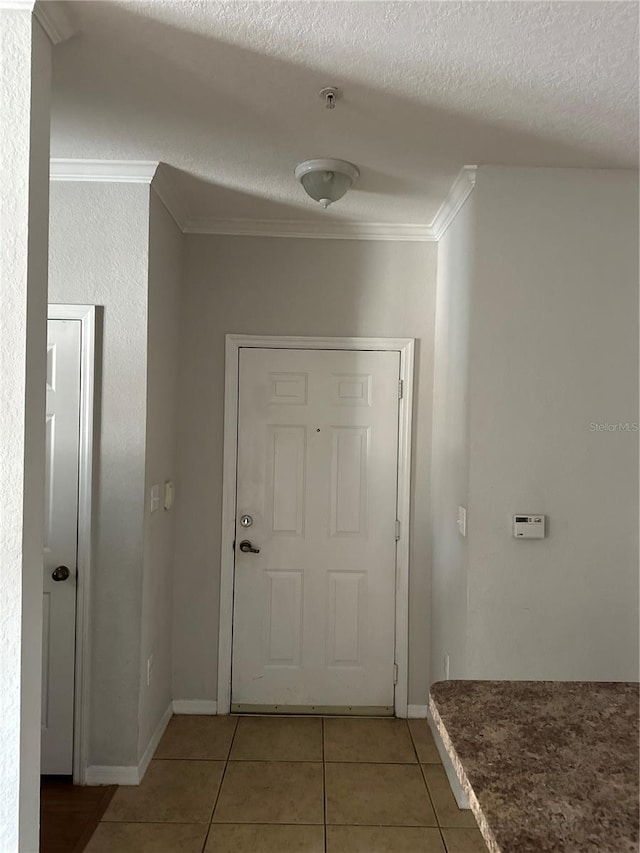 hall with light tile patterned flooring, crown molding, a textured ceiling, and baseboards