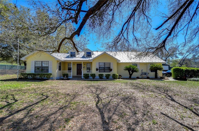 view of front of home with metal roof, covered porch, and fence