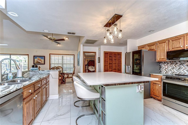 kitchen with marble finish floor, a sink, a center island, stainless steel appliances, and decorative backsplash