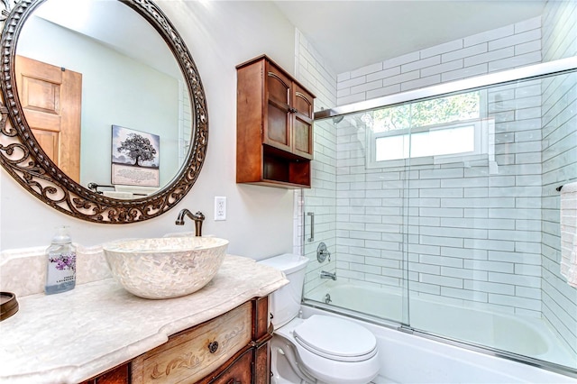 bathroom with combined bath / shower with glass door, toilet, and vanity