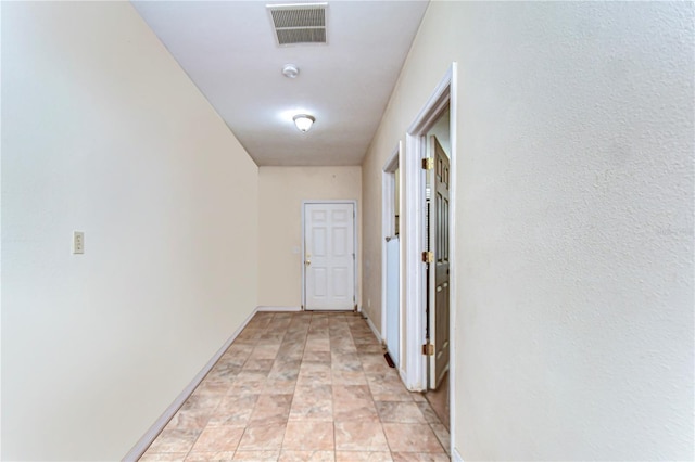 hall featuring baseboards and visible vents