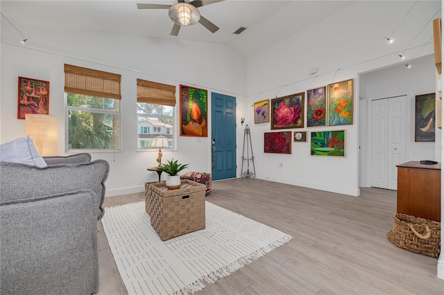 interior space with visible vents, ceiling fan, baseboards, lofted ceiling, and light wood-style floors