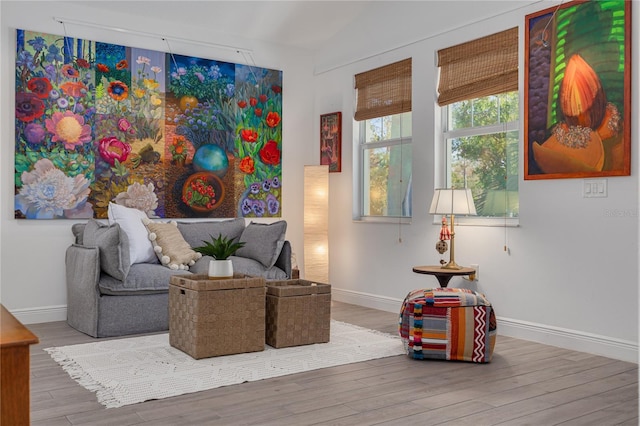 living area with vaulted ceiling, wood finished floors, and baseboards