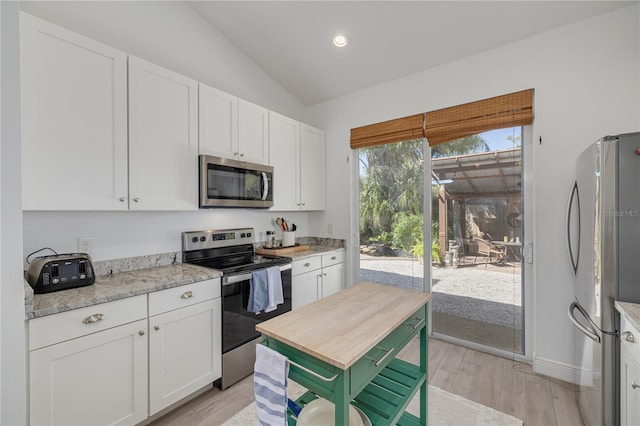 kitchen with light wood finished floors, lofted ceiling, recessed lighting, stainless steel appliances, and white cabinets