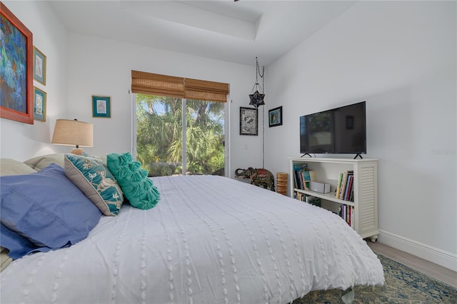 bedroom featuring access to exterior, baseboards, and wood finished floors