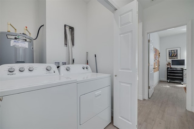 laundry area featuring baseboards, washing machine and dryer, light wood-type flooring, water heater, and laundry area