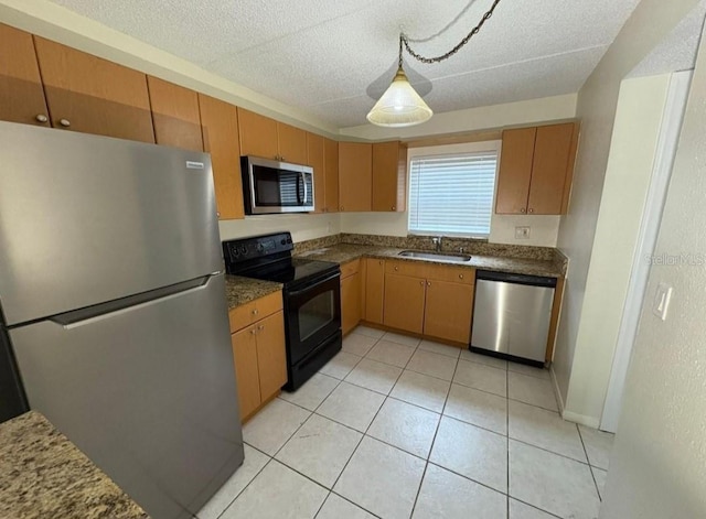 kitchen featuring a sink, a textured ceiling, appliances with stainless steel finishes, and light tile patterned floors