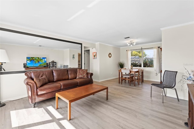 living room featuring crown molding, baseboards, and light wood-type flooring