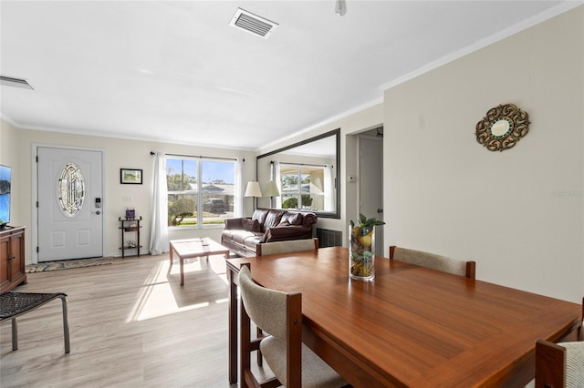 dining space with crown molding, light wood-style floors, and visible vents