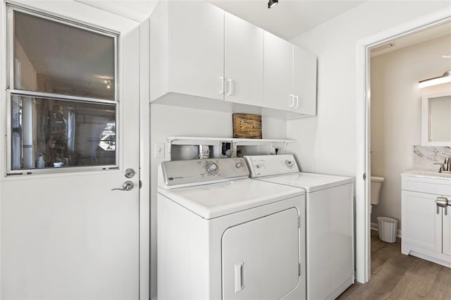 washroom with a sink, cabinet space, light wood-type flooring, and independent washer and dryer