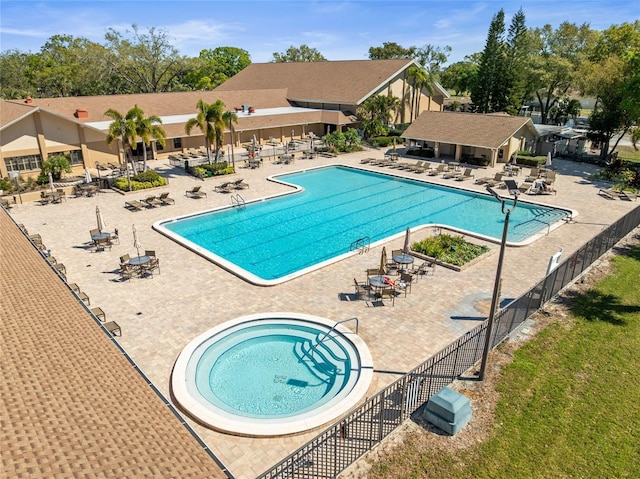 community pool with a patio area and fence