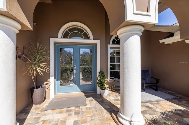 property entrance featuring stucco siding and french doors