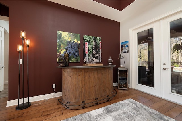 bar featuring french doors, baseboards, beverage cooler, and hardwood / wood-style floors