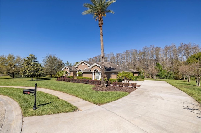 view of front of house with stucco siding, a front yard, and driveway