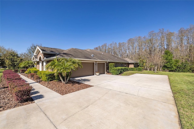 view of side of property with a lawn, an attached garage, and driveway