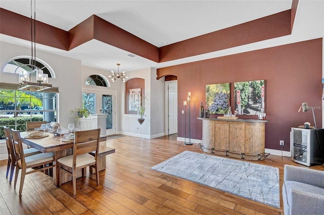 dining space featuring hardwood / wood-style floors, baseboards, arched walkways, and a chandelier