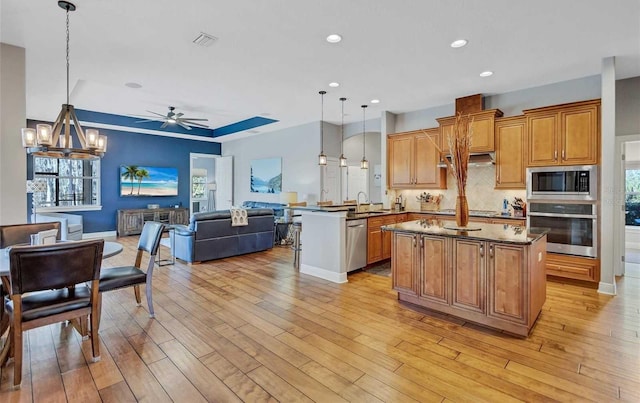 kitchen featuring visible vents, a sink, stainless steel appliances, ceiling fan with notable chandelier, and open floor plan