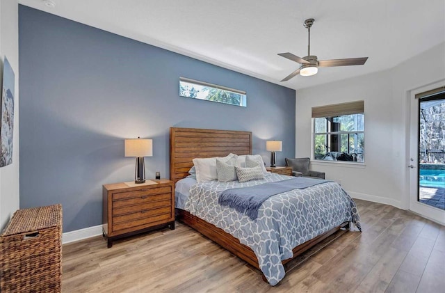 bedroom with access to outside, multiple windows, baseboards, and wood finished floors