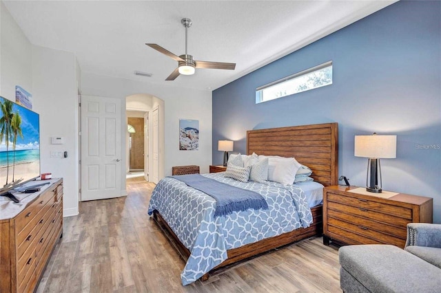 bedroom featuring wood finished floors, arched walkways, visible vents, and ceiling fan