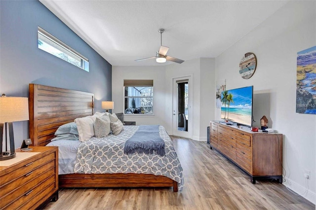 bedroom featuring multiple windows, baseboards, light wood-style floors, and access to outside