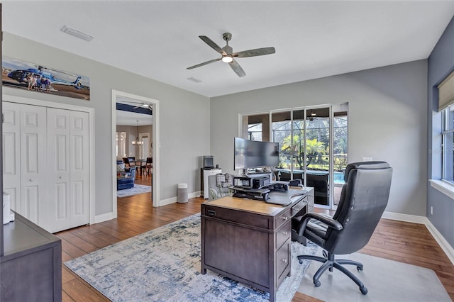 office with hardwood / wood-style floors, visible vents, baseboards, and ceiling fan