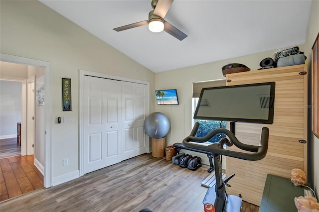 exercise room featuring vaulted ceiling, wood finished floors, baseboards, and ceiling fan