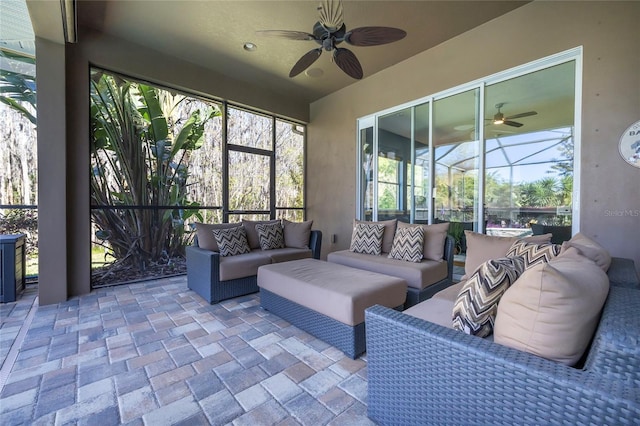 view of patio featuring glass enclosure, a ceiling fan, and outdoor lounge area