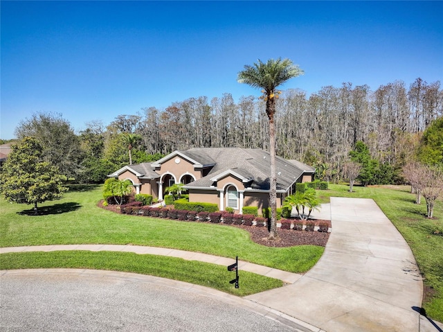 view of front of house with concrete driveway, a front yard, and stucco siding