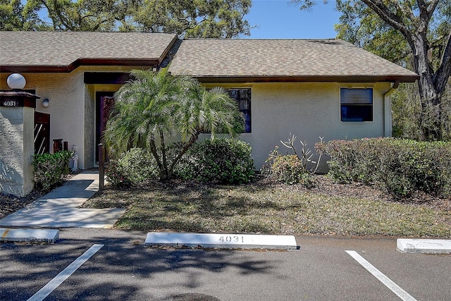 view of front of home featuring a shingled roof, uncovered parking, and stucco siding