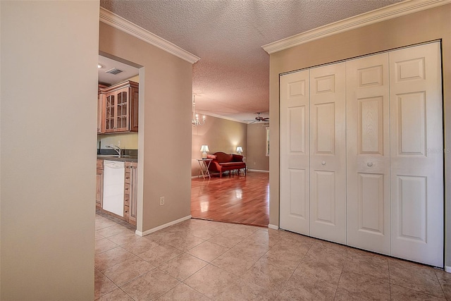 hall featuring a textured ceiling, an inviting chandelier, crown molding, light tile patterned floors, and baseboards