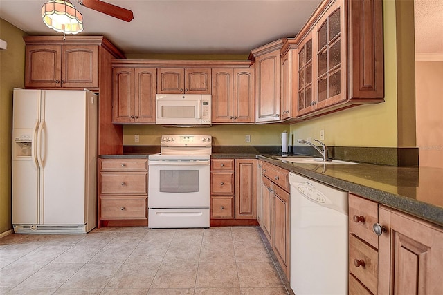 kitchen with glass insert cabinets, light tile patterned floors, brown cabinetry, white appliances, and a sink