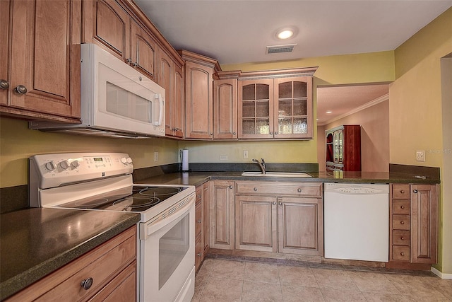 kitchen with white appliances, dark countertops, visible vents, and a sink