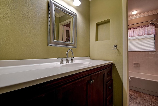 bathroom with crown molding, toilet, wood finished floors, a textured wall, and vanity