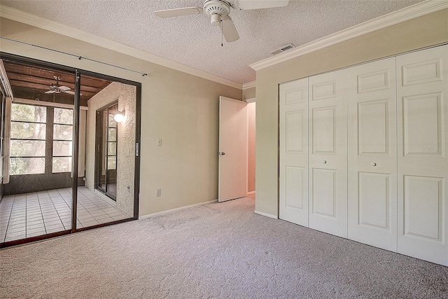 unfurnished bedroom with visible vents, ornamental molding, a textured ceiling, a closet, and carpet flooring