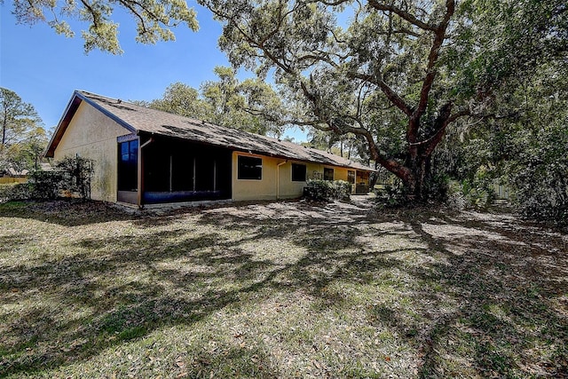 back of house with a sunroom and stucco siding