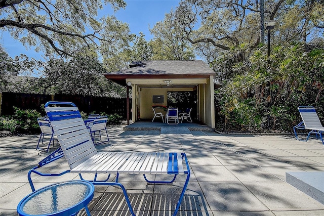 view of patio featuring an outbuilding, outdoor dining area, and fence