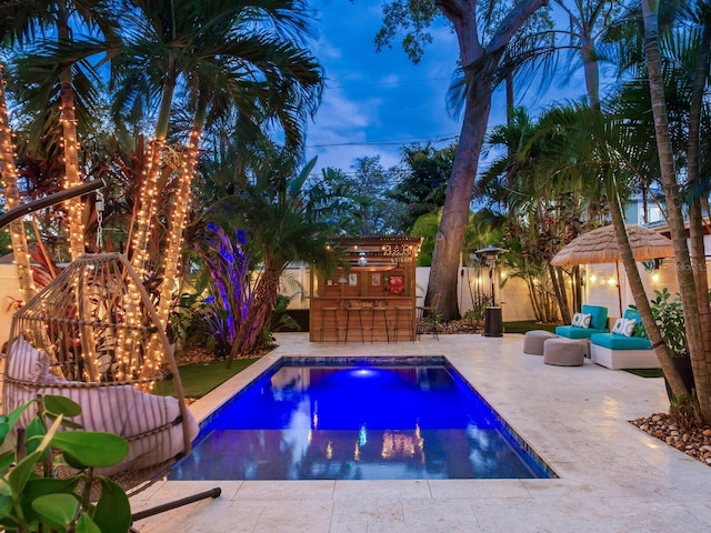 outdoor pool featuring a patio, a fenced backyard, and outdoor dry bar