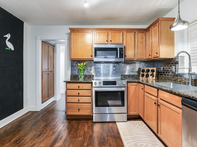 kitchen with dark wood-type flooring, a sink, tasteful backsplash, stainless steel appliances, and baseboards