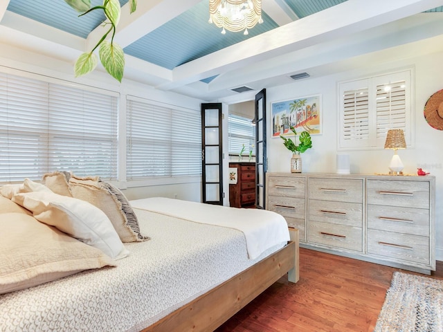 bedroom featuring beamed ceiling, wood finished floors, and visible vents