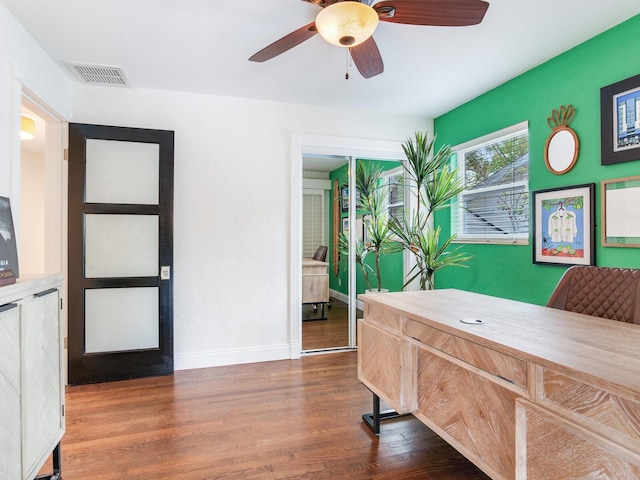 bedroom with a ceiling fan, wood finished floors, visible vents, and baseboards